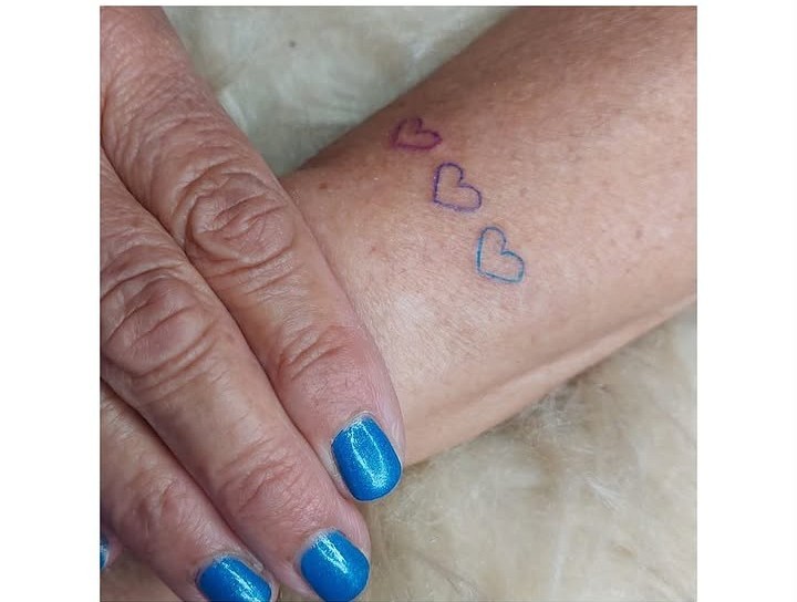 Tres corazones diminutos tatuados en los dedos
